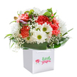 Bursting with character, this uplifting bouquet-presented in a sleek white gift bag-mirrors the spirit of New Malden's community. Abundant coral and blush carnations, each intricately frilled, mingle with luminous white daisies whose chartreuse-green centers shine like sunlight filtering through suburban gardens. Whimsical sprays of baby's breath create a gentle, airy weave amid the blossoms, while glossy green leaves arc gracefully around the design, providing both contrast and a sense of natural abundance. A scattering of purple-tinged buds, quietly awaiting their moment, adds depth and interest to the cheerful display. Every stem is purposefully placed, the rounded bouquet echoing the happy gatherings found in New Malden's local parks and streets. Sturdy white handles top the polished gift bag, making it ready for hand delivery with ease. Flooded with bright, clean light, the arrangement radiates freshness-a heartfelt gift for celebrating milestones, offering comfort, or simply brightening a neighbour's day across New Malden.